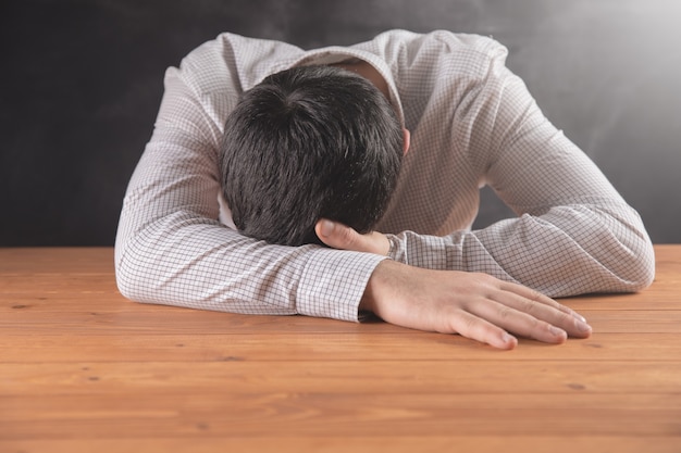 Man sleeping on a wooden table .