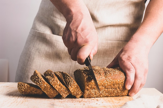 A man slices large knife with fresh bread with golden crust The concept of home baking cooking diet food without yeast