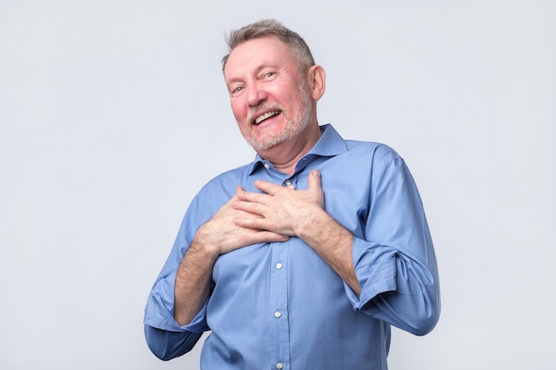 Man smiles happily keeps hands on chest