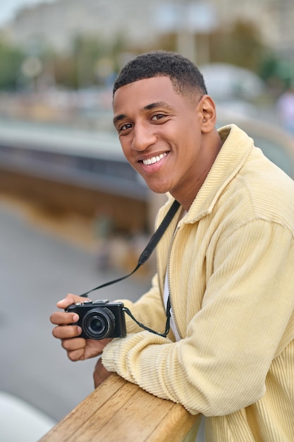 Man smiling at camera leaning on railing in street