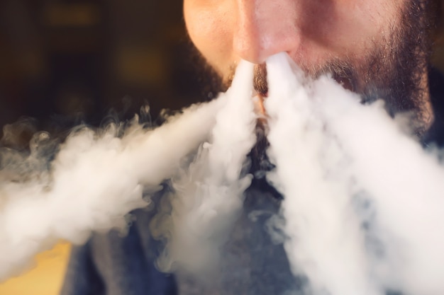 Photo the man smoke an electronic cigarette at the vape shop