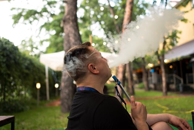 Man smoking shesha, hookah hookahs in nature on a warm Sunny day. Eastern hookah Smoking, active rec