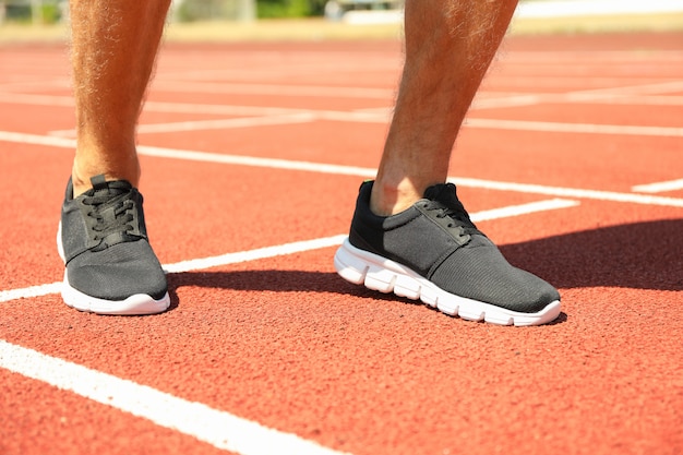 Man in sneakers on red athletic running track, close up