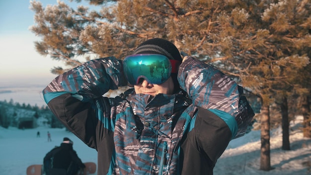 A man snowboarder putting on protective glasses