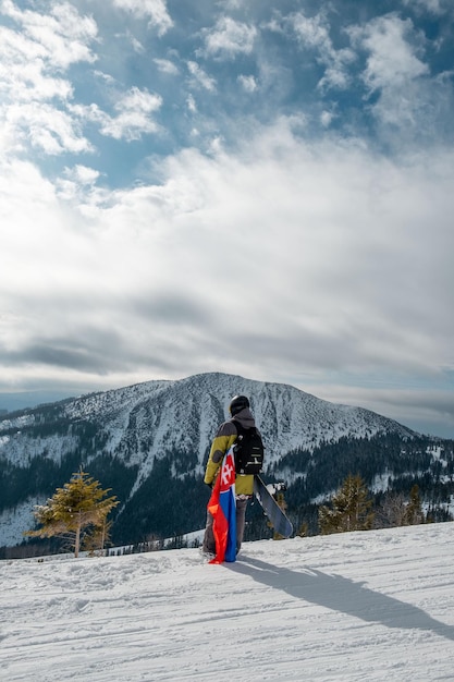 Man snowboarder with slovakia flag at ski resort slope