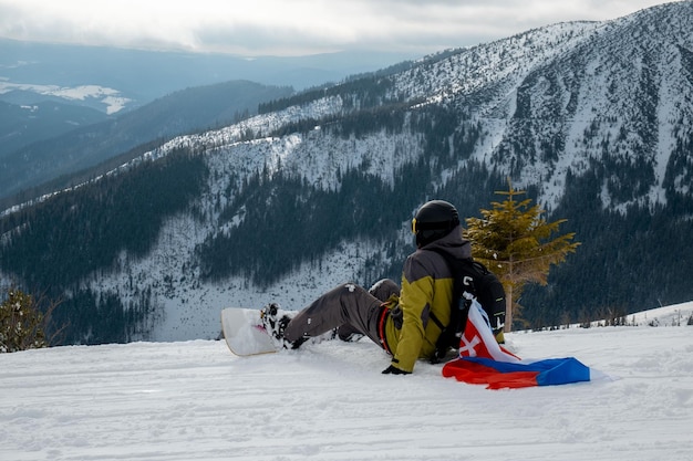 Man snowboarder with slovakia flag at ski resort slope