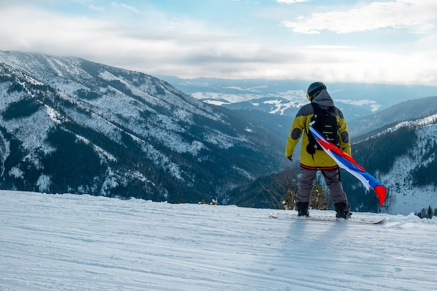 Man snowboarder with slovakia flag at ski resort slope