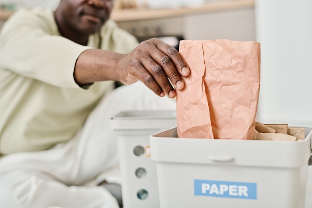 Man sorting paper in container