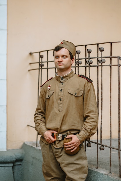 A man in a Soviet world war II uniform stands at the yellow wall