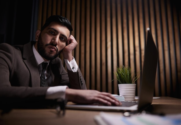 A man of spanish appearance works at the office with a laptop