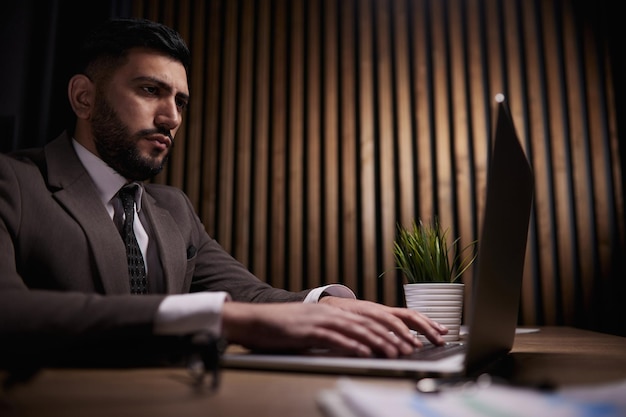 A man of spanish appearance works at the office with a laptop