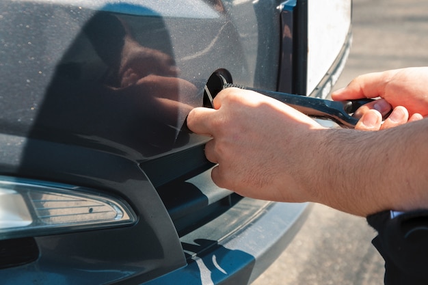 A man spins a hook for towing in front of a car. Car breakdown and towing.