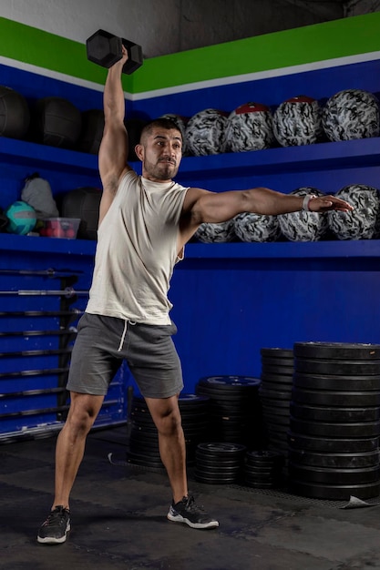 Man in sportswear doing dumbbell lifts at the gym vertical photo