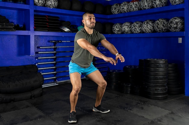 Man in sportswear doing squats in a crossfit gym