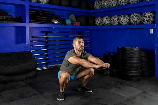 Man in sportswear doing squats in a crossfit gym