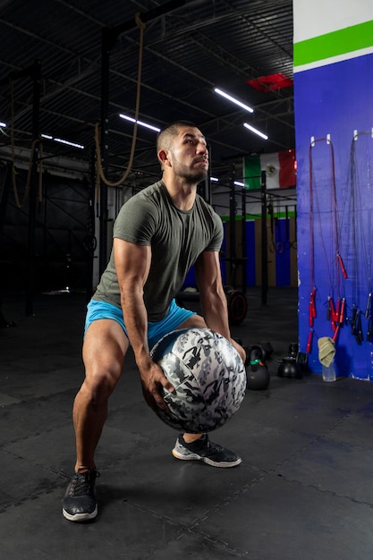 Man in sportswear exercising with a crossfit medicine ball in a gym