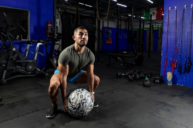 Man in sportswear exercising with a crossfit medicine ball in a gym