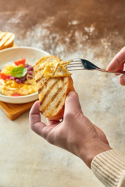 The man spread baked camembert cheese with onions and jam on the bread in a plate. Close-up, selecti