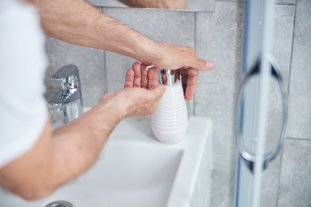  man squeezing a small amount of liquid soap into his palm