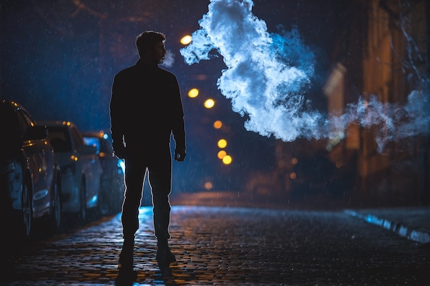 The man stand near the cloud of smoke. Evening night time