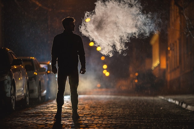 The man stand near the smoke. Evening night time. Telephoto lens shot