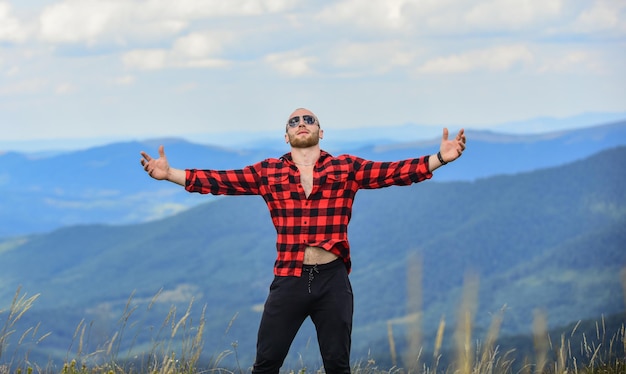 Man stand on top of mountain Hug whole world Hiking concept Active leisure Guy enjoy freedom Masculinity and male energy Achieve freedom Free and wild Value of freedom Self sufficient