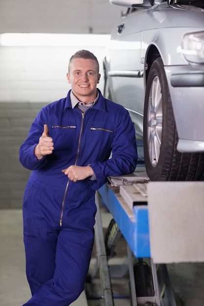 Man standing next to a car with his thumb up