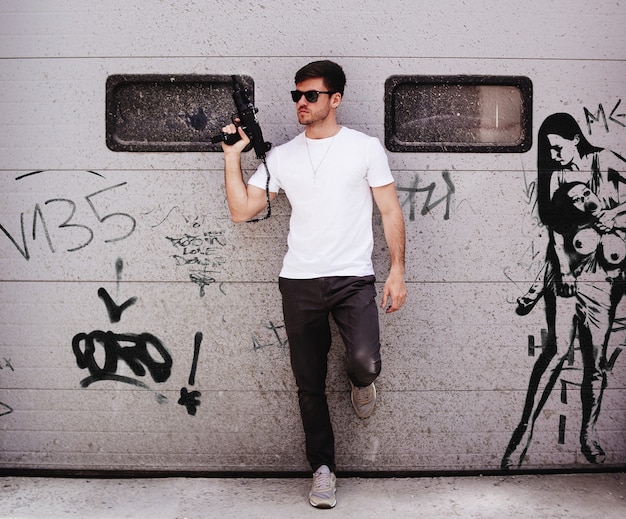 A man standing next to a graffiti covered wall