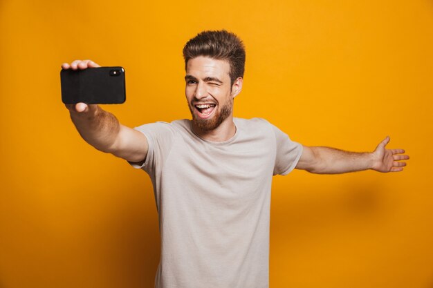 Photo man standing isolated make a selfie by smartphone showing copyspace.