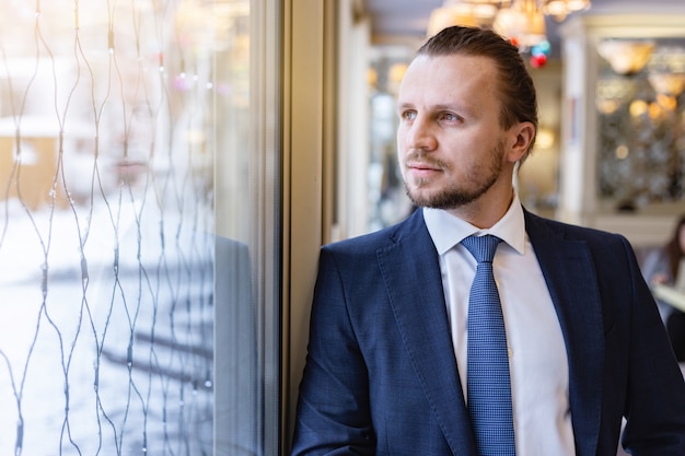 Man standing and looking dreamly  in the window indoor