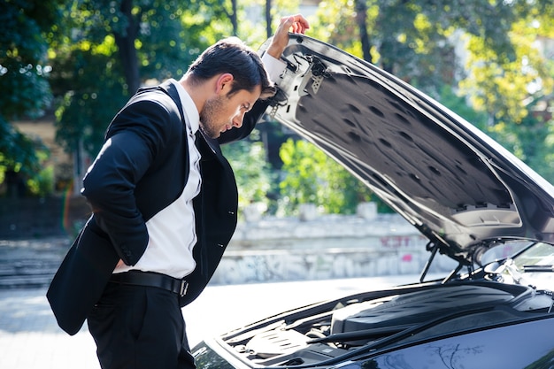 Man standing near broken car with open hood