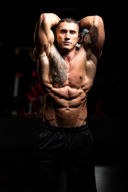 Man Standing Strong In The Gym And Flexing Muscles Muscular Athletic Bodybuilder Fitness Model Posing After Exercises