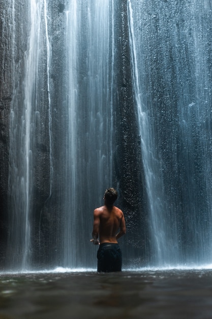 Man Standing Under Stunning Waterfall in Bali Indonesia