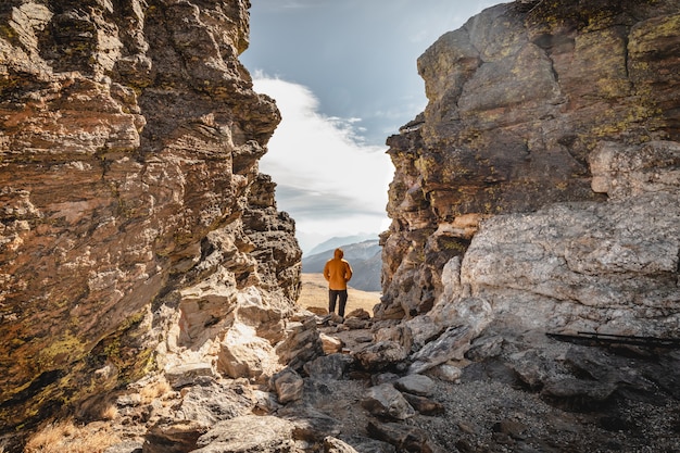 Man standing on a summit  between rocks in the Rocky Mountain National Park and looking over the mountain range on a coldand windy day