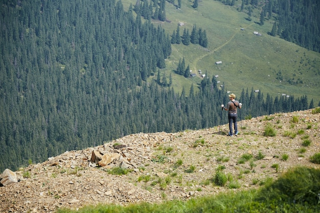 Man standing on the top of rock with mountain and forest view