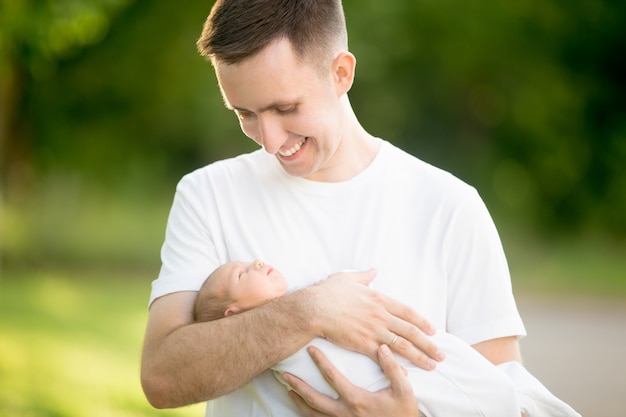 Man standing with a baby in her arms in the park