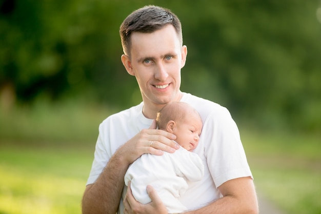 Man standing with a baby in her arms in the park