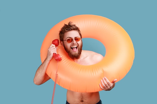 Man standing with rubber ring and talking on phone handset and looking at camera with toothy smile