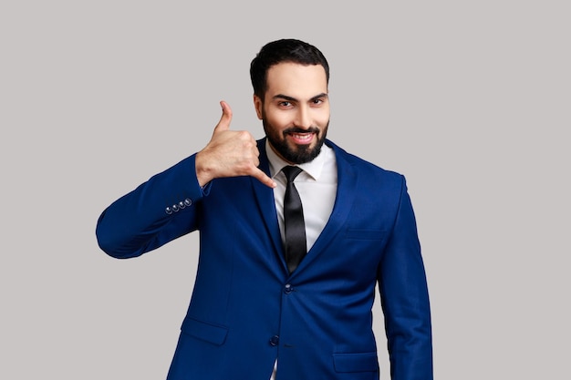 Man standing with telephone hand gesture and smiling to camera flirting offering to contact by phone