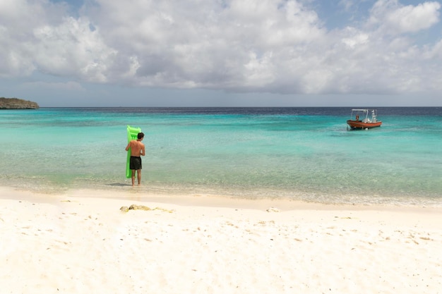 a man stands on a beach with a green water float in the beach