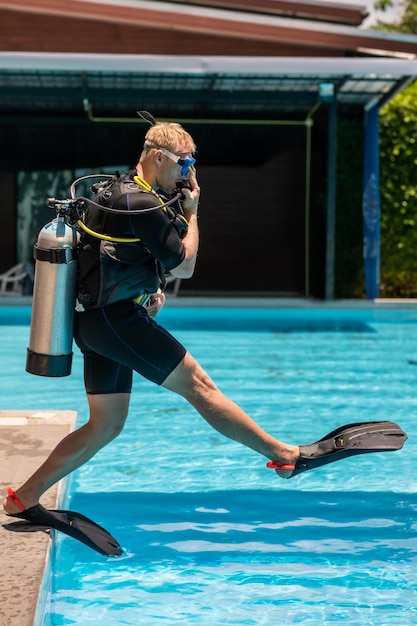 A man stands in diving equipment and is ready to dive under the water in the pool