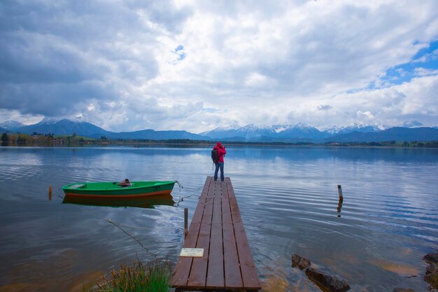 a man stands on a dock next to a green canoe