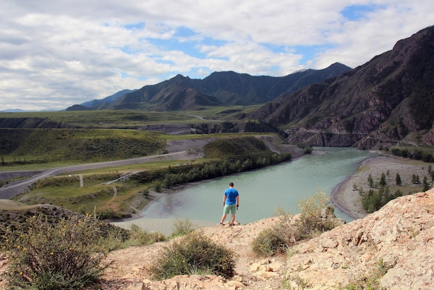 A man stands on the edge of a mountain and looks at a beautiful mountain landscape from a height