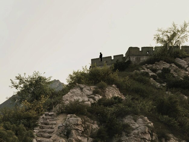 Photo a man stands on a hill overlooking a building with a man on the top