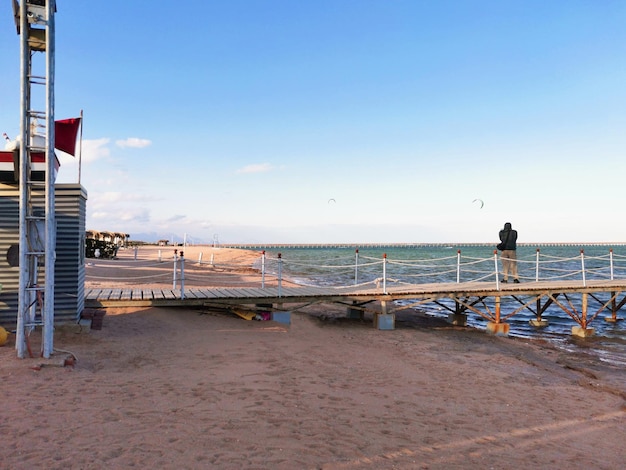 Man stands on the pier and takes pictures of paragliding