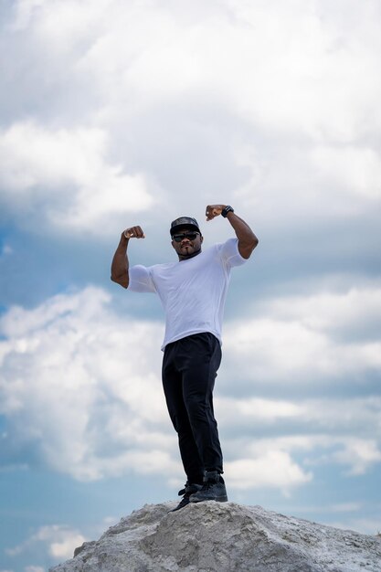 Man stands on rock and shows his muscles