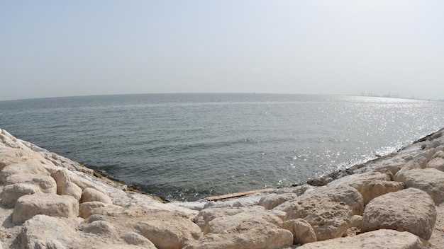 A man stands on a rocky shore next to the ocean.