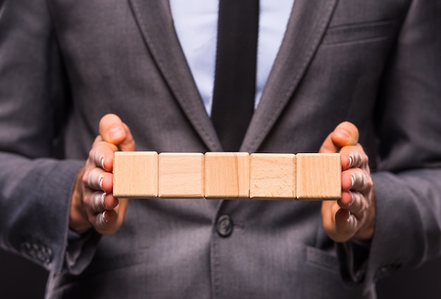 A man stands in a suit and holds cubes.