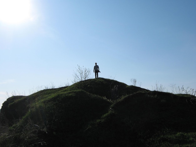 Photo a man stands on the top of a hill high hill mountain