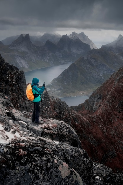 a man stands on top of the mountain and takes a photo on his mobile phone